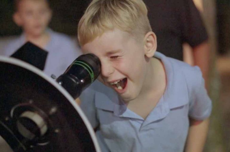 Një burrë dërgon teleskopin në rrugë, njerëzit shikojnë hënën