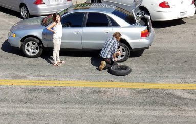 I pastrehu i ndërron gomën e makinës një gruaje