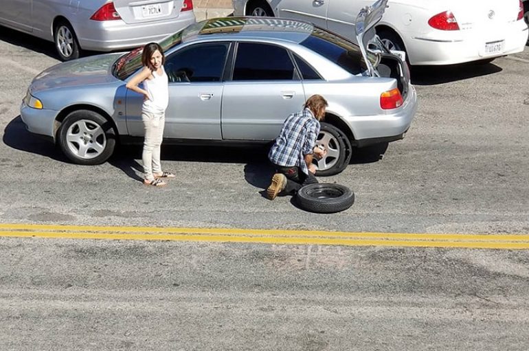 I pastrehu i ndërron gomën e makinës një gruaje